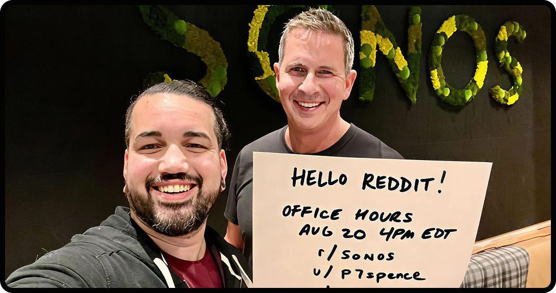 Two men holding up a piece of paper with their office hours on it.