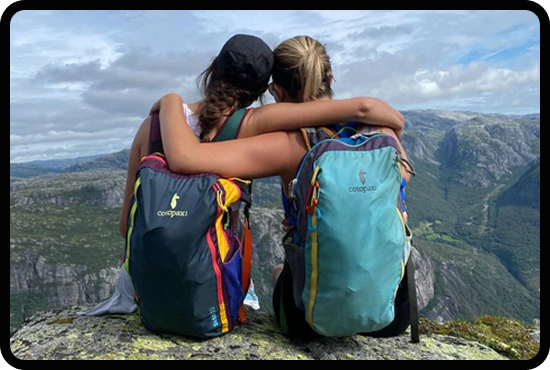 Photo of two women embracing with Cotopaxi backpacks