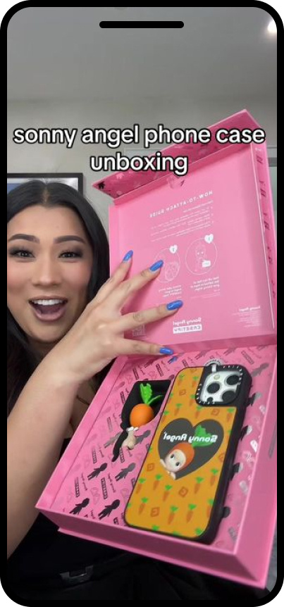 A woman holding a pink box with a phone case inside