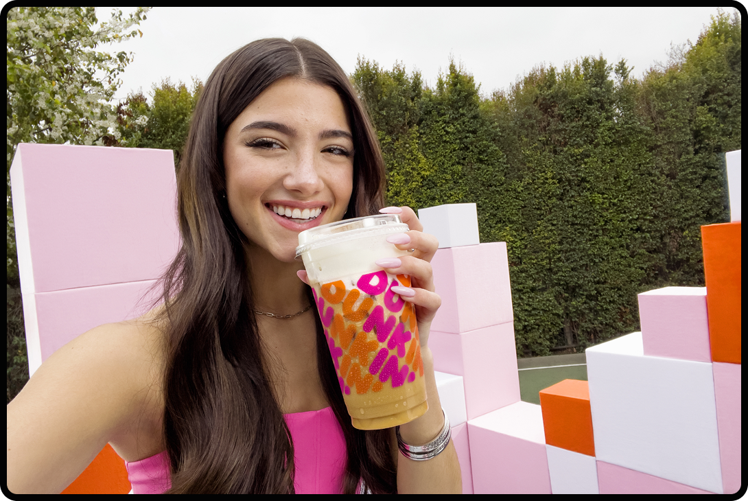 Charli D'Amelio holding a cup of Dunkin Donuts coffee.