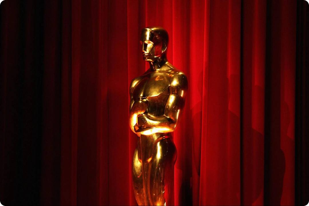 Image of an Oscar trophy on a red curtain backdrop.